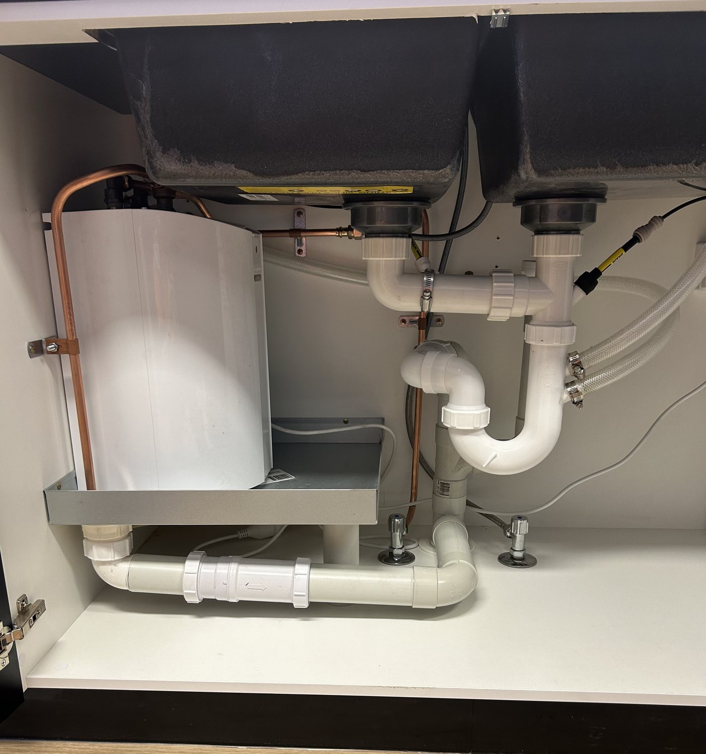 Continuous flow hot water unit and pipework under a kitchen sink